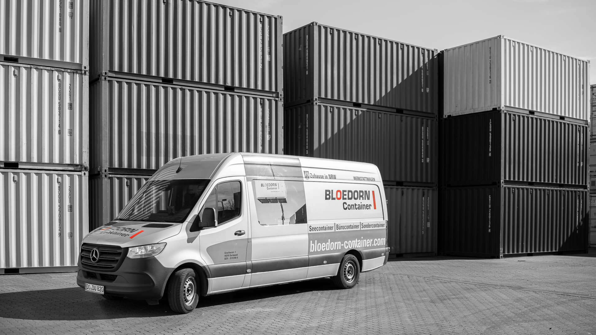 Firmenwagen vor Containern